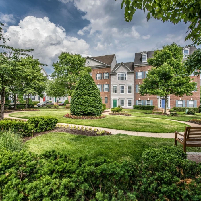 Beautifully landscaped apartment courtyard featuring winding sidewalks, manicured gardens, and large mature trees