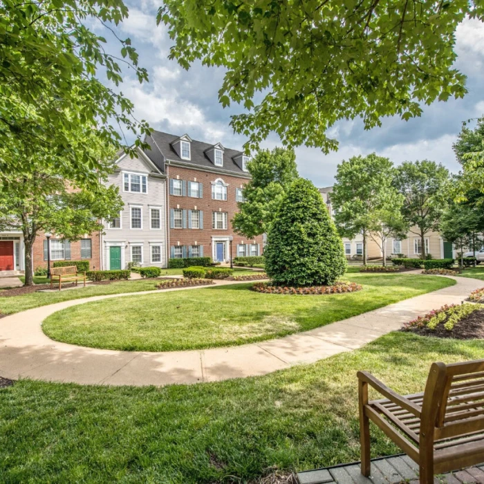 Lush landscaped courtyard surrounded by apartment buildings featuring circular walking path and green space