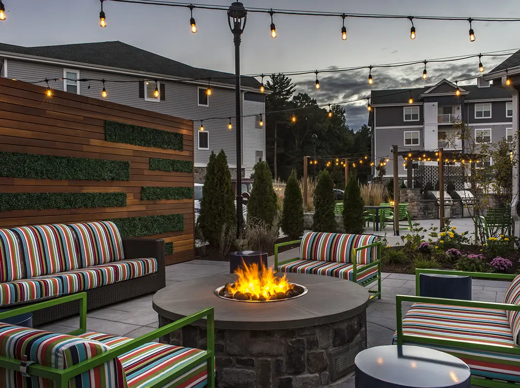 Three friends laugh around a grill on a summer afternoon