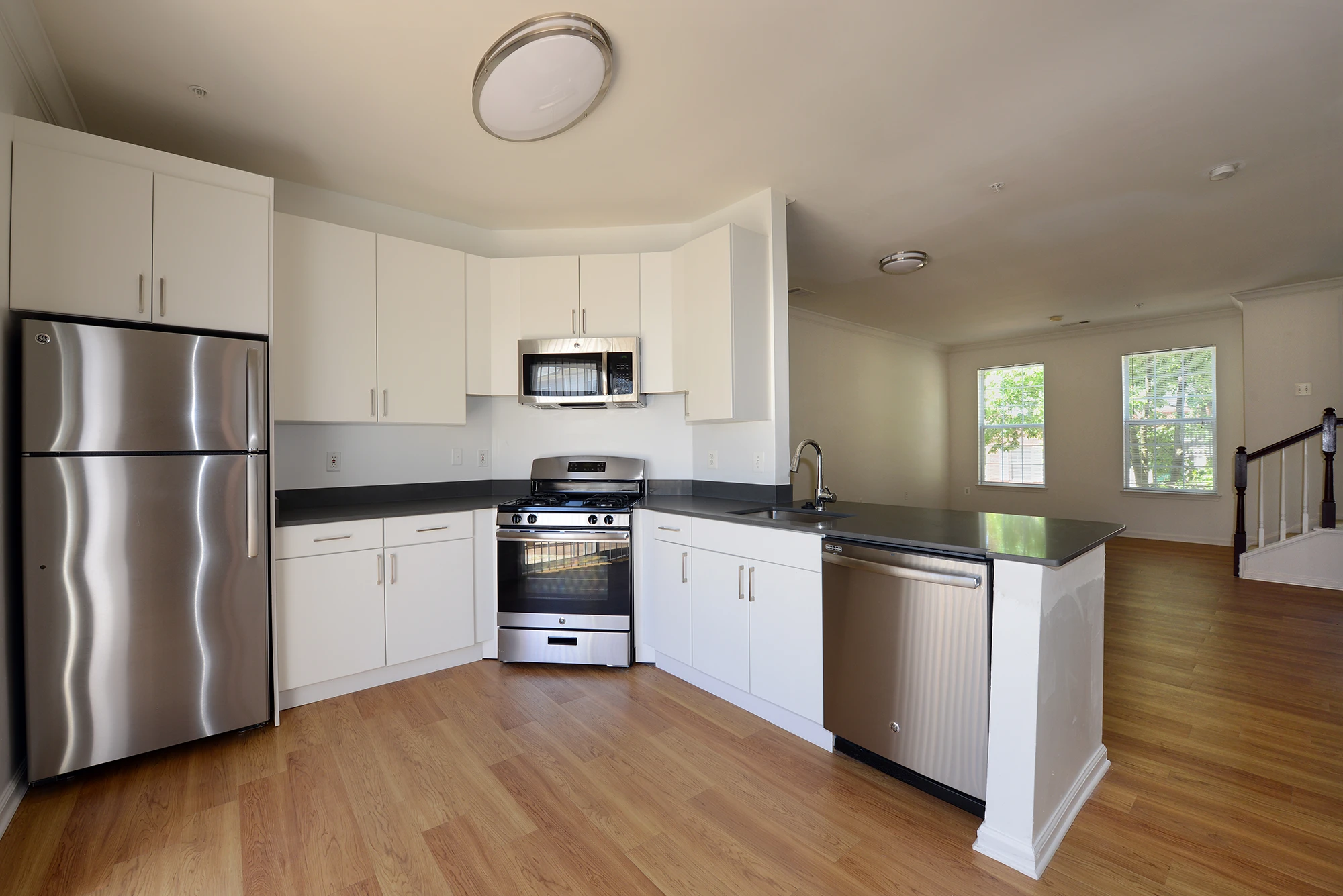 Bright apartment kitchen featuring refrigerator, stove, microwave, and dishwasher within an open-concept layout
