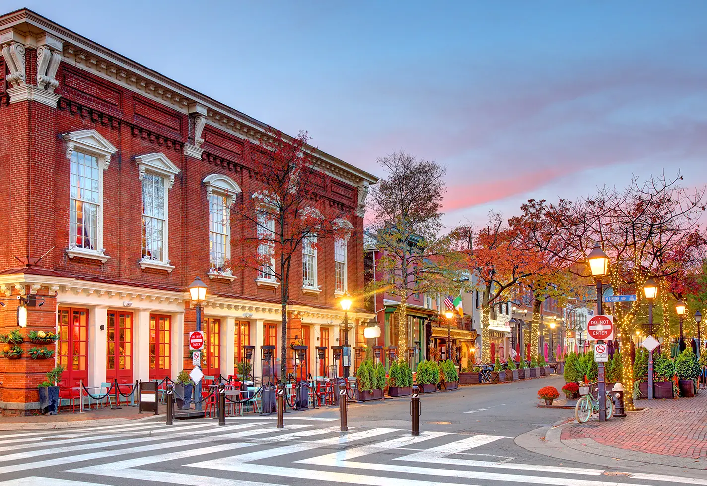 Charming brick buildings along Old Town Alexandria street with colorful outdoor dining and evening lights