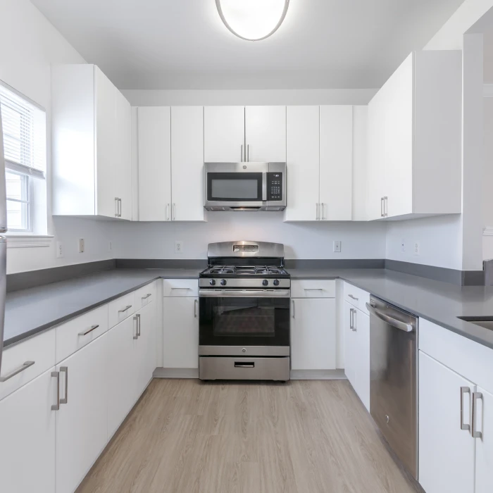 Updated kitchen design with modern appliances, ample counter space, and wood-style flooring in apartment