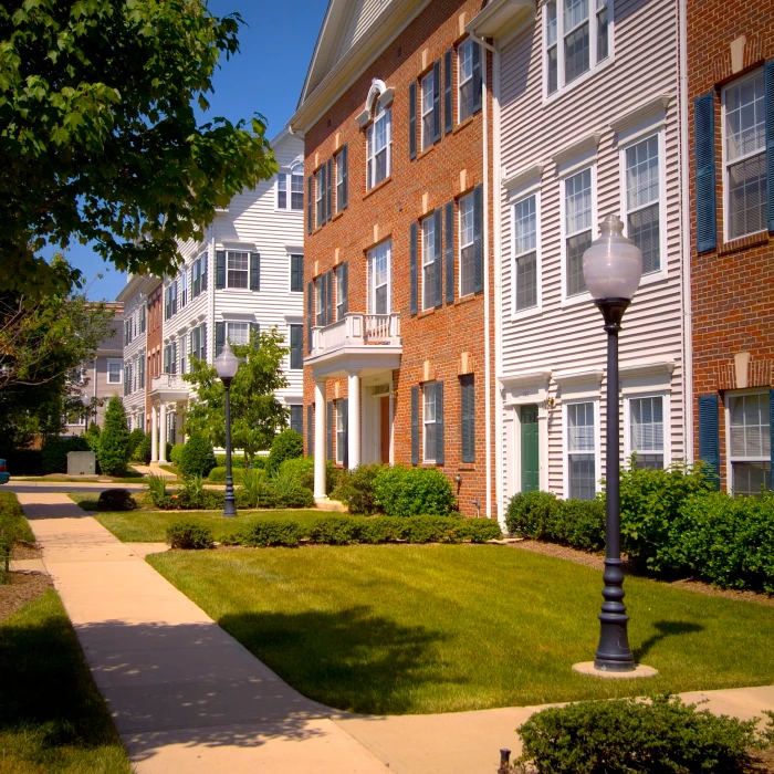 Brick and siding apartment building exterior with bright green lawn and traditional black streetlamps