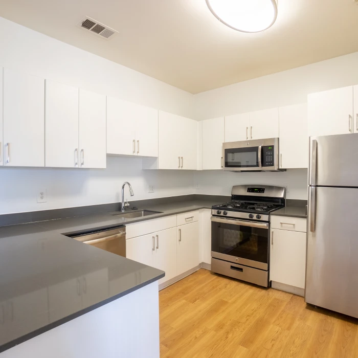 Bright modern kitchen with wood-style flooring, microwave, gas stove, and spacious cabinetry for storage