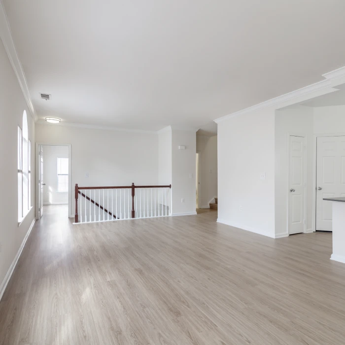 Bright open-concept apartment interior featuring light wood flooring, neutral walls, and stainless steel appliances
