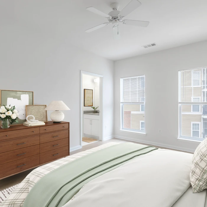 Bright modern apartment bedroom featuring stylish decor, cozy bed, dresser, and private bathroom entrance